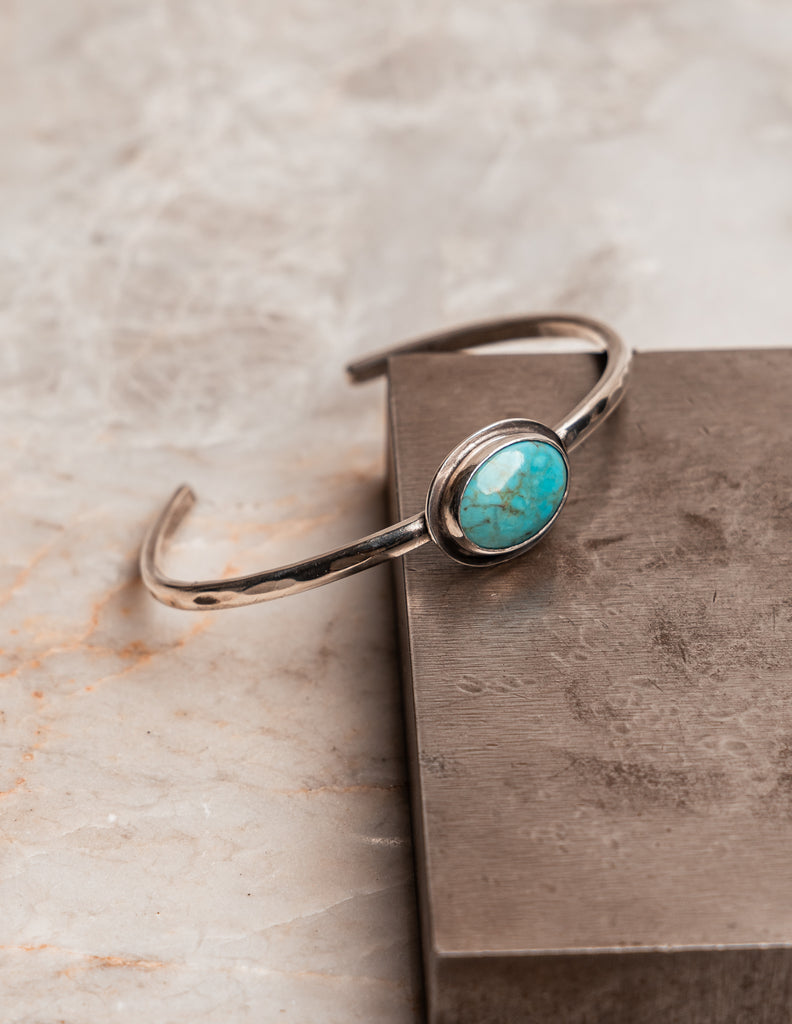 "Hand-forged Anika Cuff with natural turquoise gemstone, adjustable silver bracelet."

