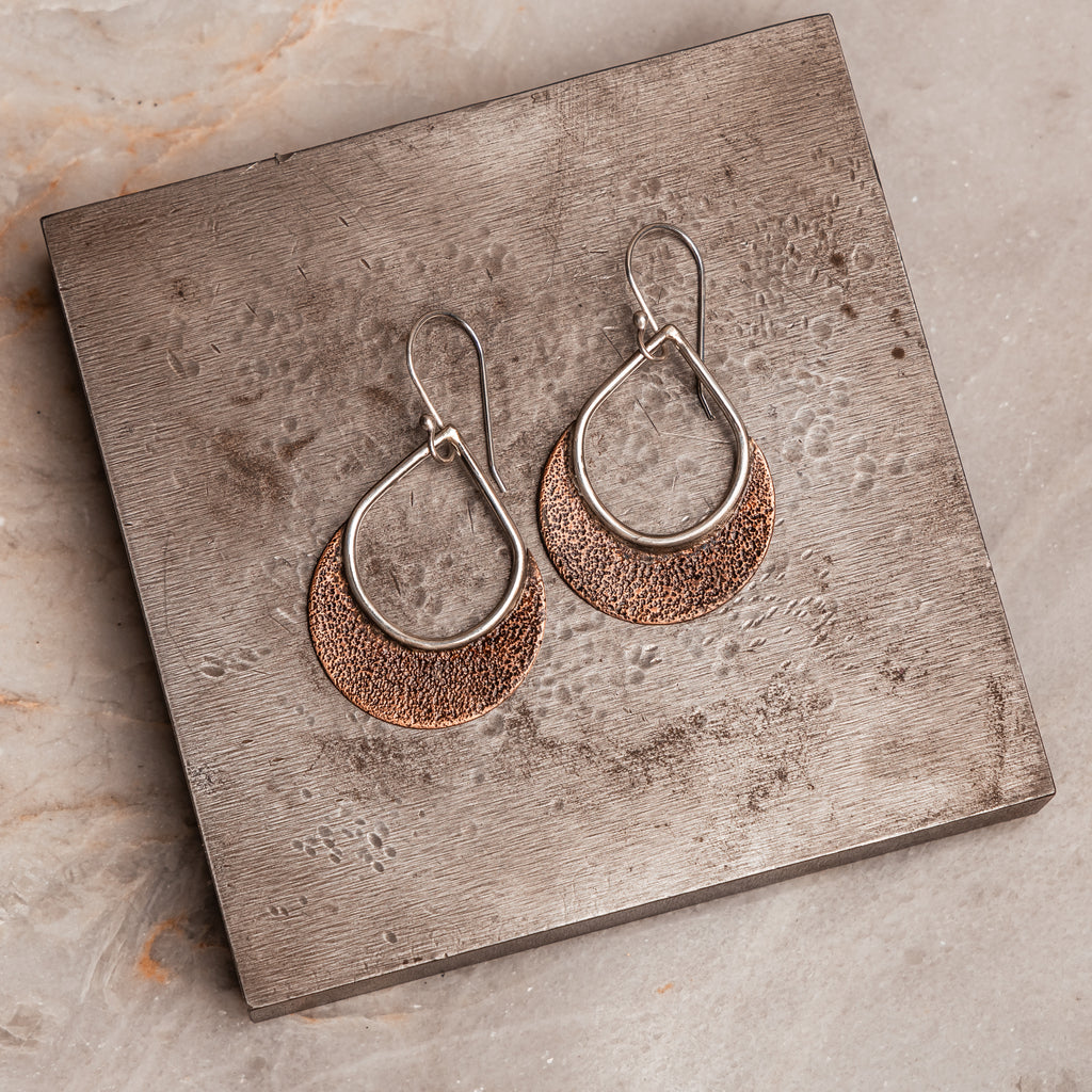 "Boho-style Delphine Earrings displaying artisan-forged copper textures with sterling silver ear wires."

