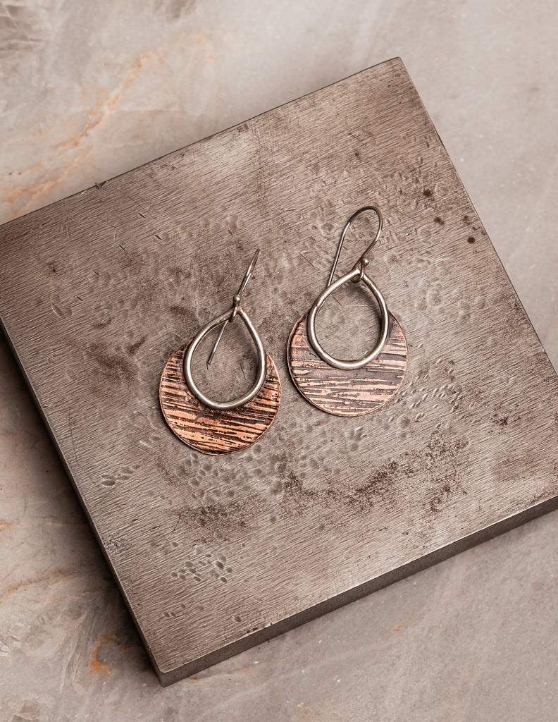 "Boho-style Delphine Earrings displaying artisan-forged copper textures with sterling silver ear wires."

