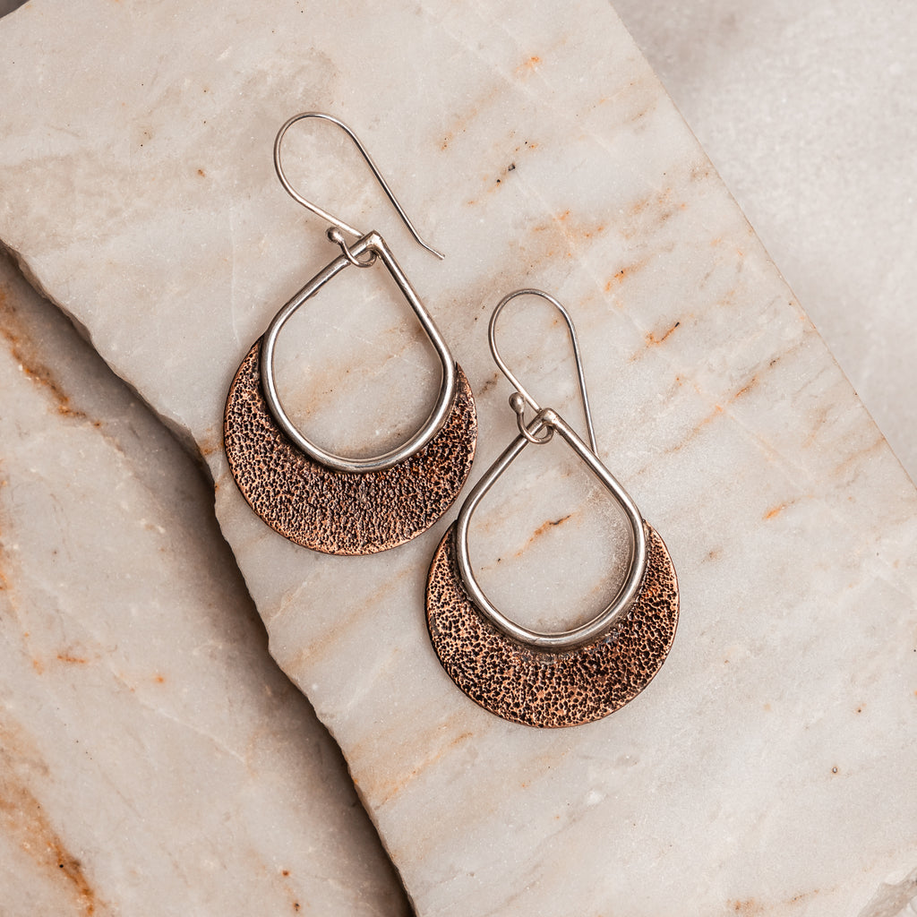 "Handcrafted Delphine Earrings showcasing unique textured copper and sterling silver in small and large sizes."

