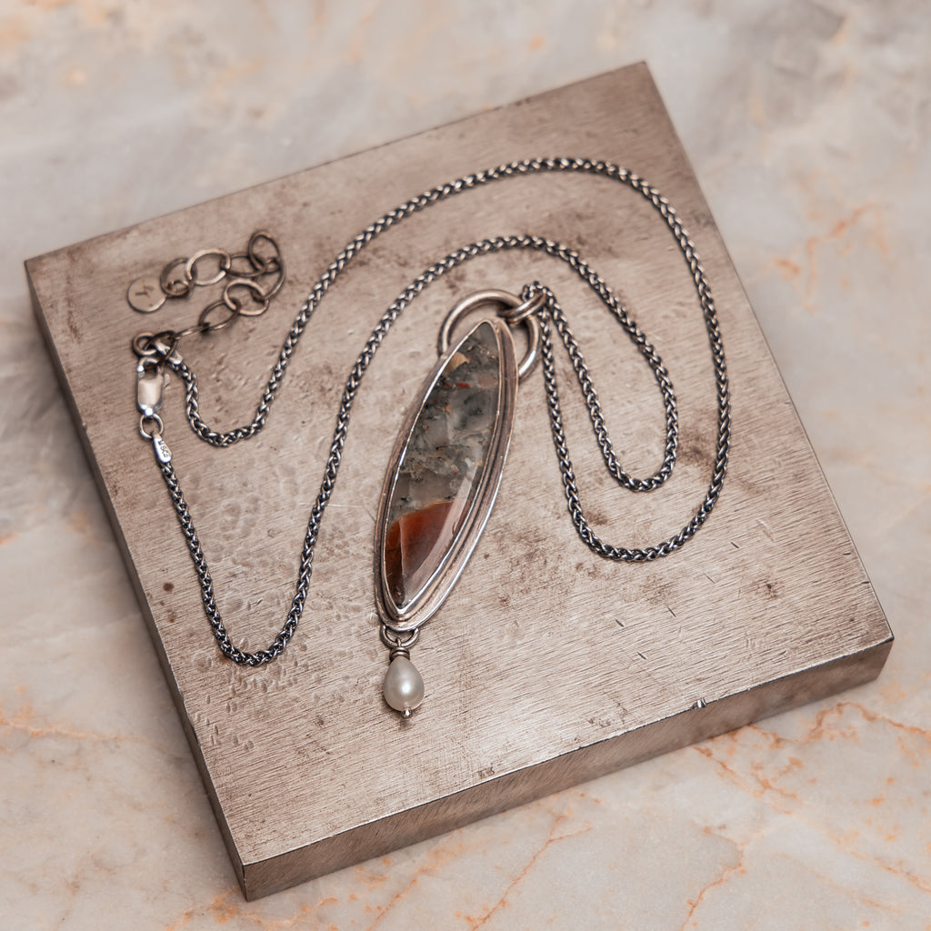 Bohemian-inspired silver pendant necklace with earthy stone and luminous pearl detail