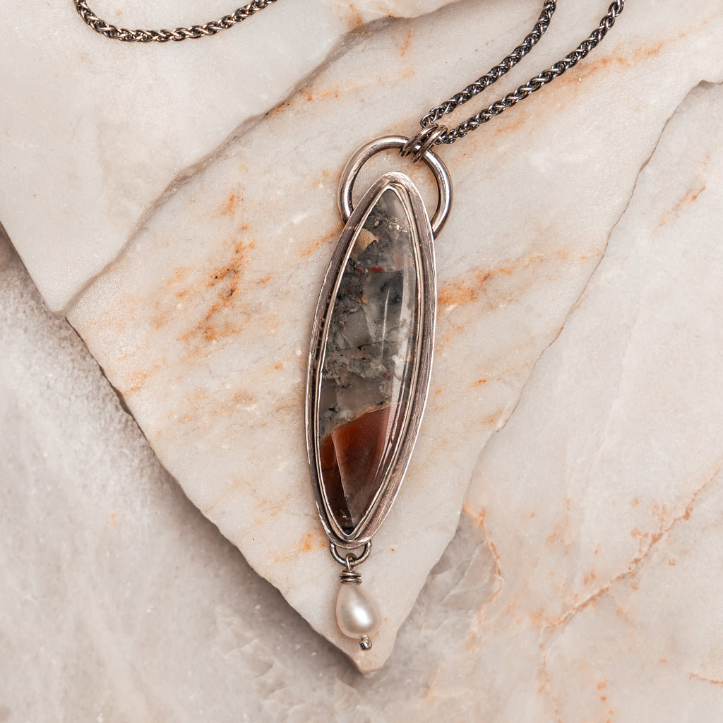 Bohemian-inspired silver pendant necklace with earthy stone and luminous pearl detail