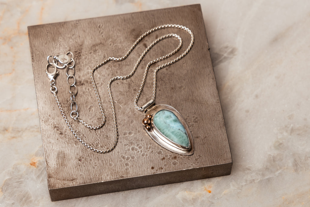 The Delta Necklace, a unique and elegant piece of jewelry, combining the beauty of larimar with the craftsmanship of sterling silver and 14k gold.