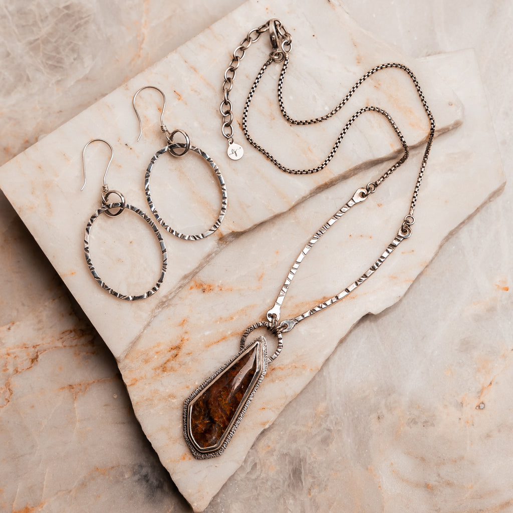 Bohemian-style silver earrings and necklace with textured ovals and artisanal craftsmanship