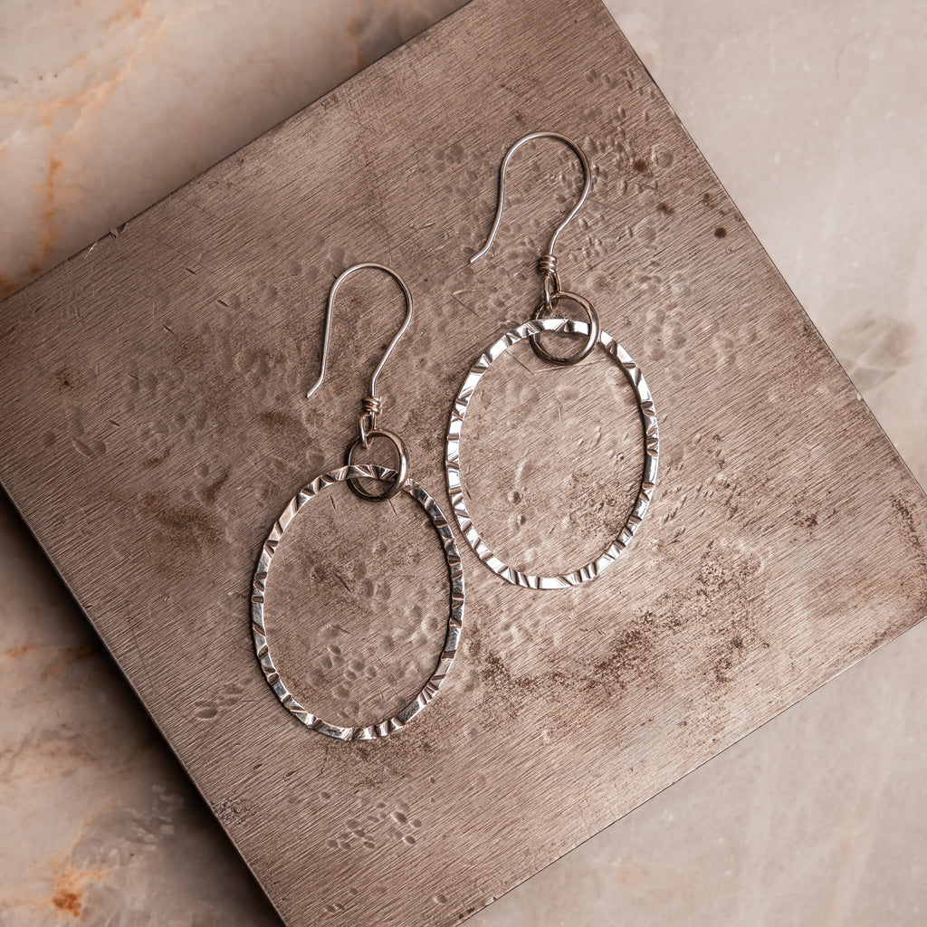 Artisan-made oval hoop earrings featuring intricate hand-hammered details