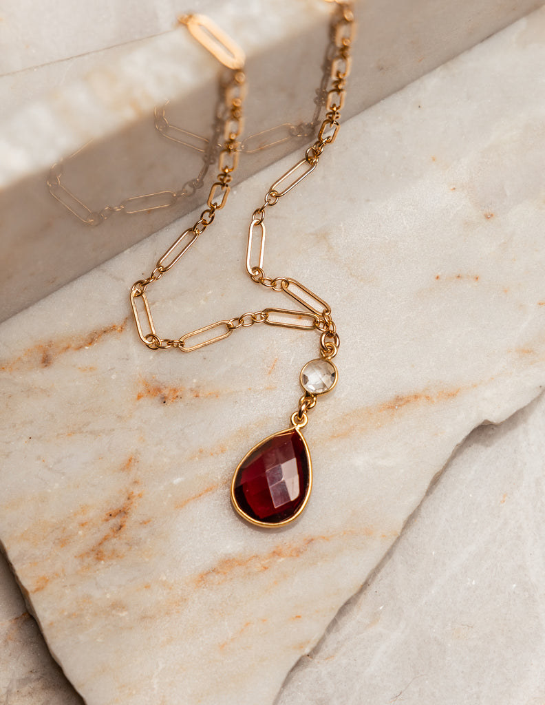 “Garnet Pendant Necklace: Leighton Jewelry Design”: Gold overlay chain with a faceted garnet pendant, accented by crystal quartz. Perfect for special occasions or gifts.