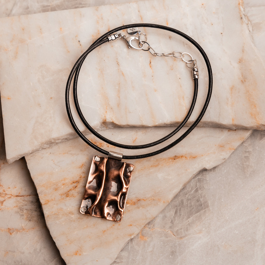 Santorini-inspired pendant necklace featuring hammered copper and sterling silver